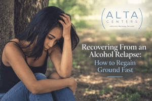 A young woman sits alone against a tree, head in hand, in a quiet moment of recovering from an alcohol relapse.
